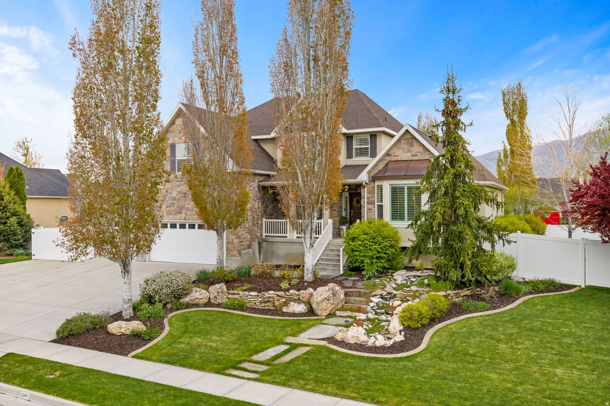 View of front of property with stone siding, concrete driveway, and roof with shingles