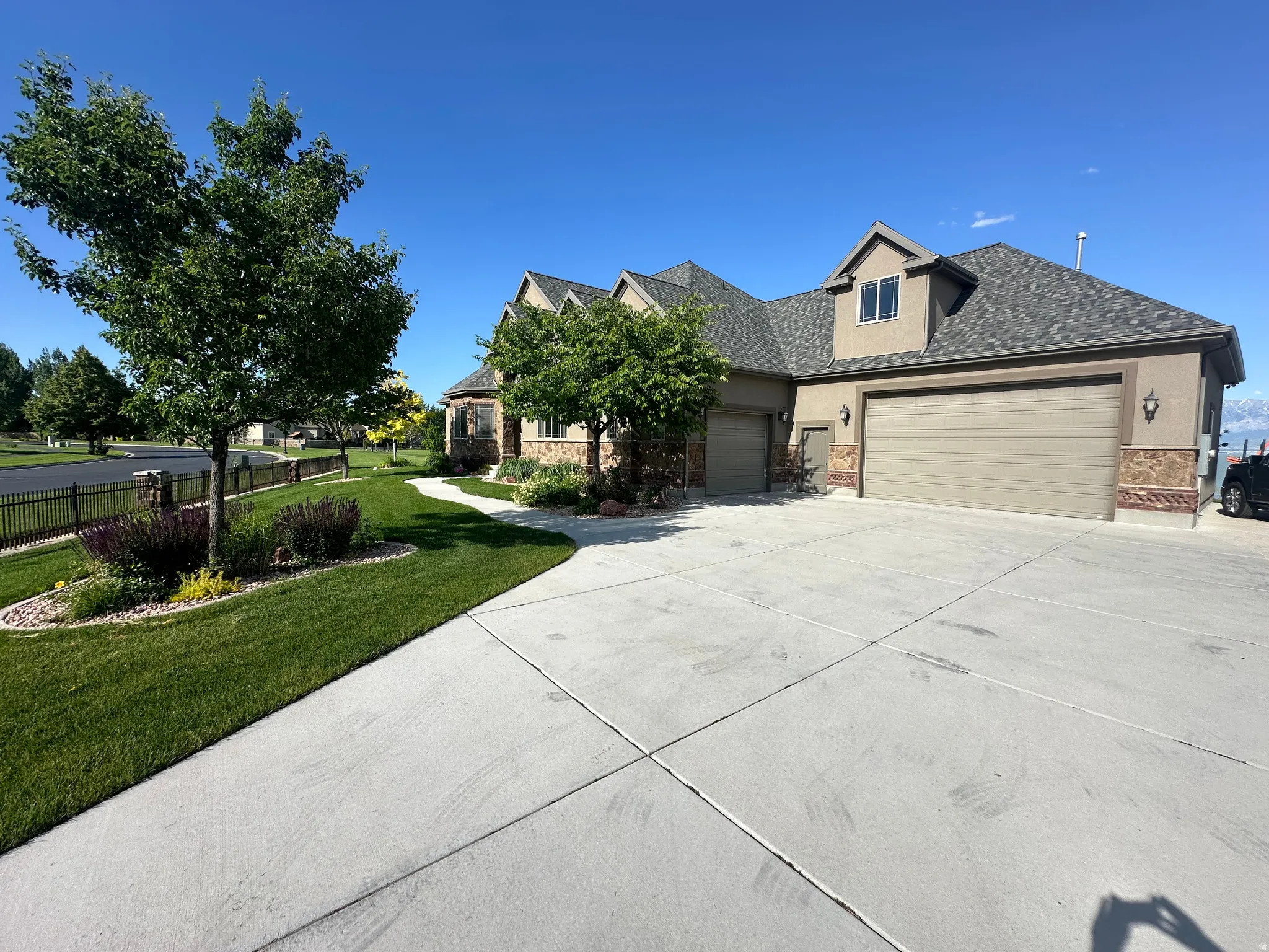 View of front of property featuring stucco siding, a garage, a front lawn, concrete driveway, and roof with shingles