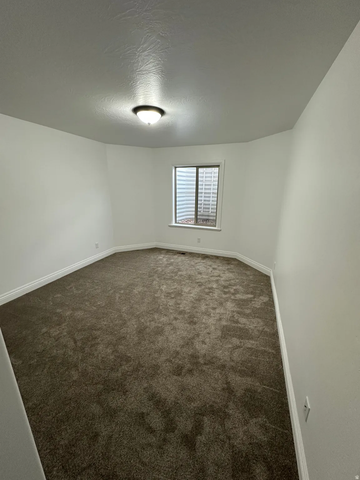 Empty room with dark carpet and a textured ceiling