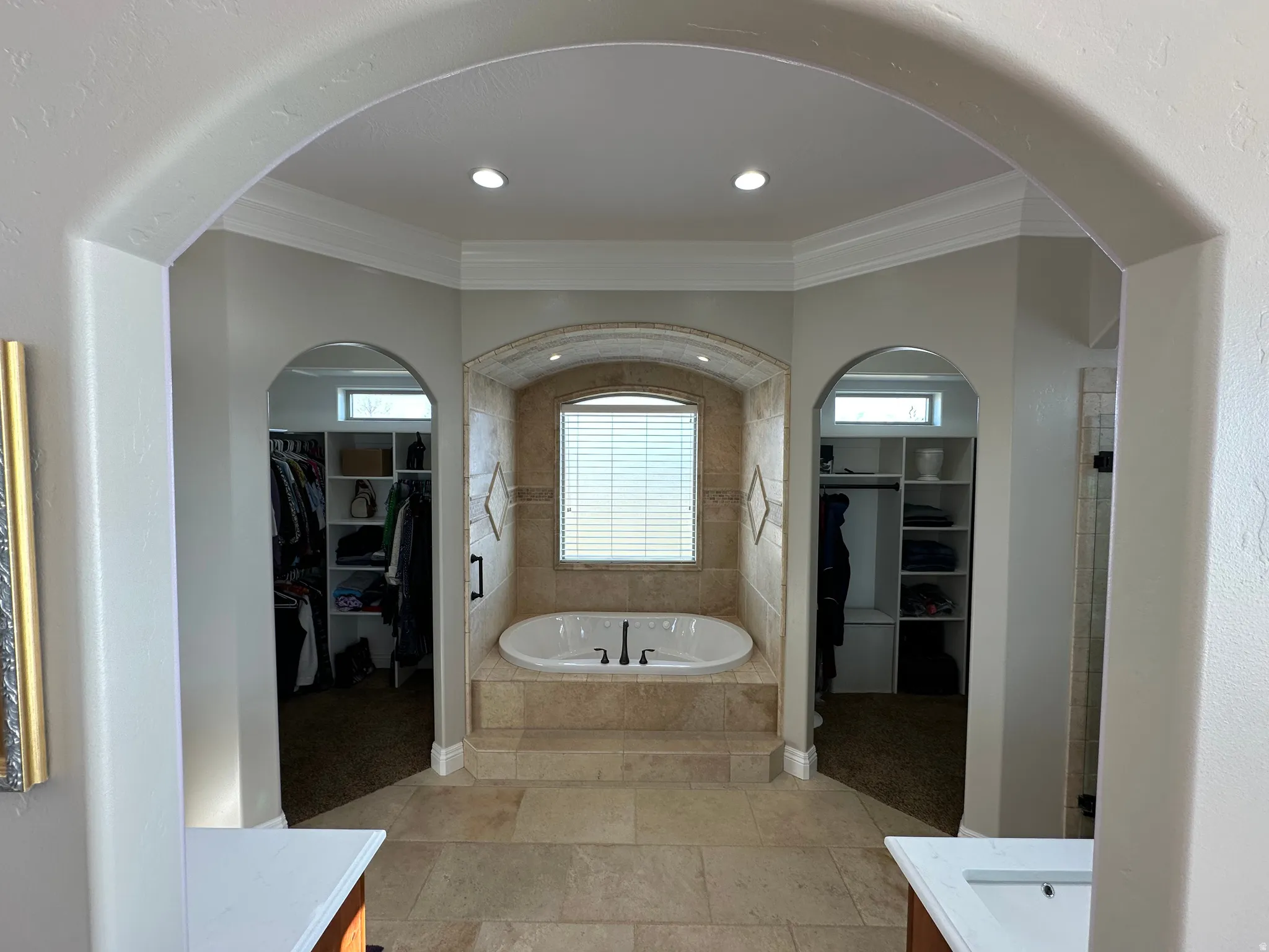Full bath with a walk in closet, vanity, a garden tub, and crown molding