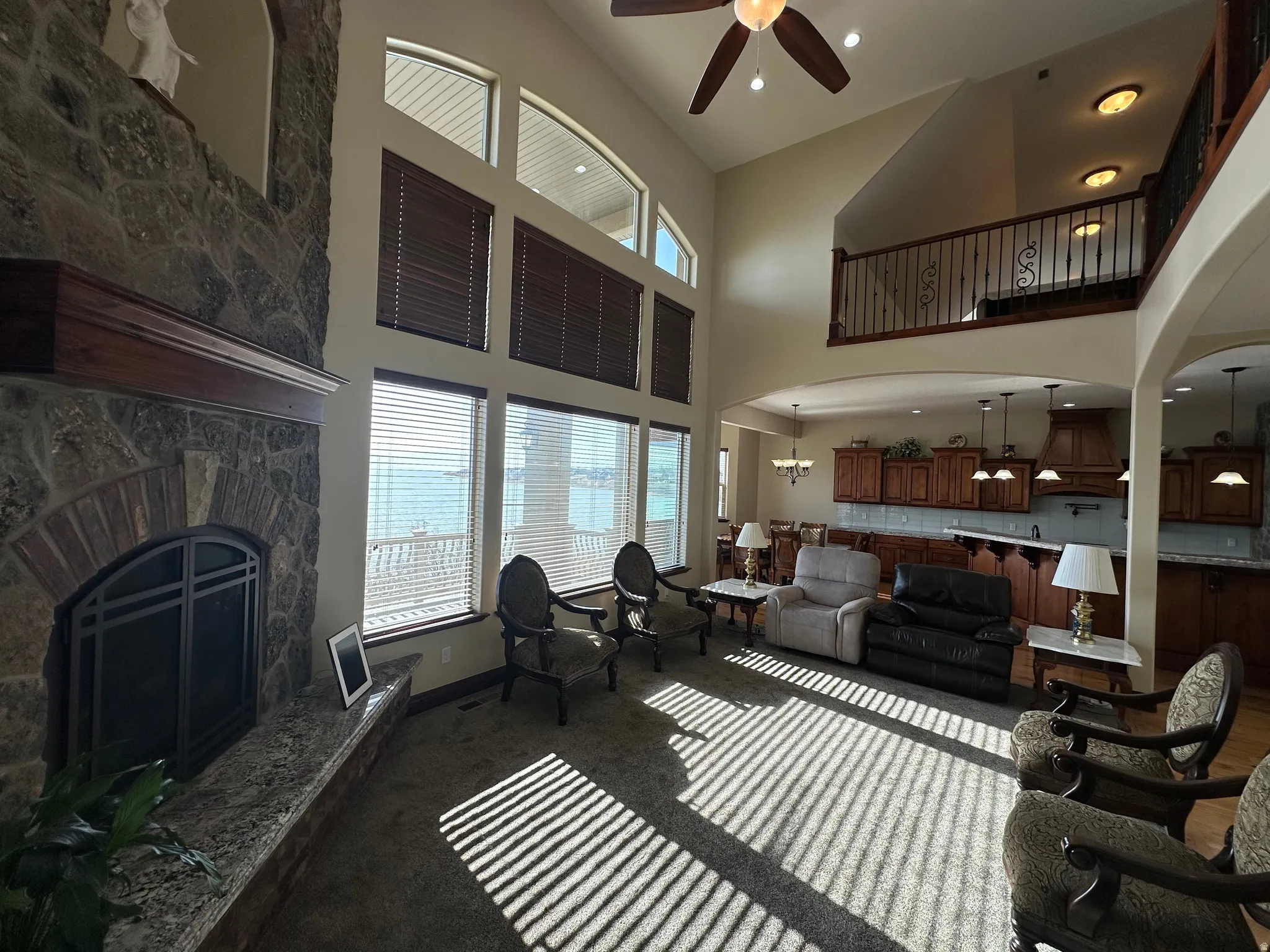 Living room with arched walkways, ceiling fan, a stone fireplace, recessed lighting, and a high ceiling