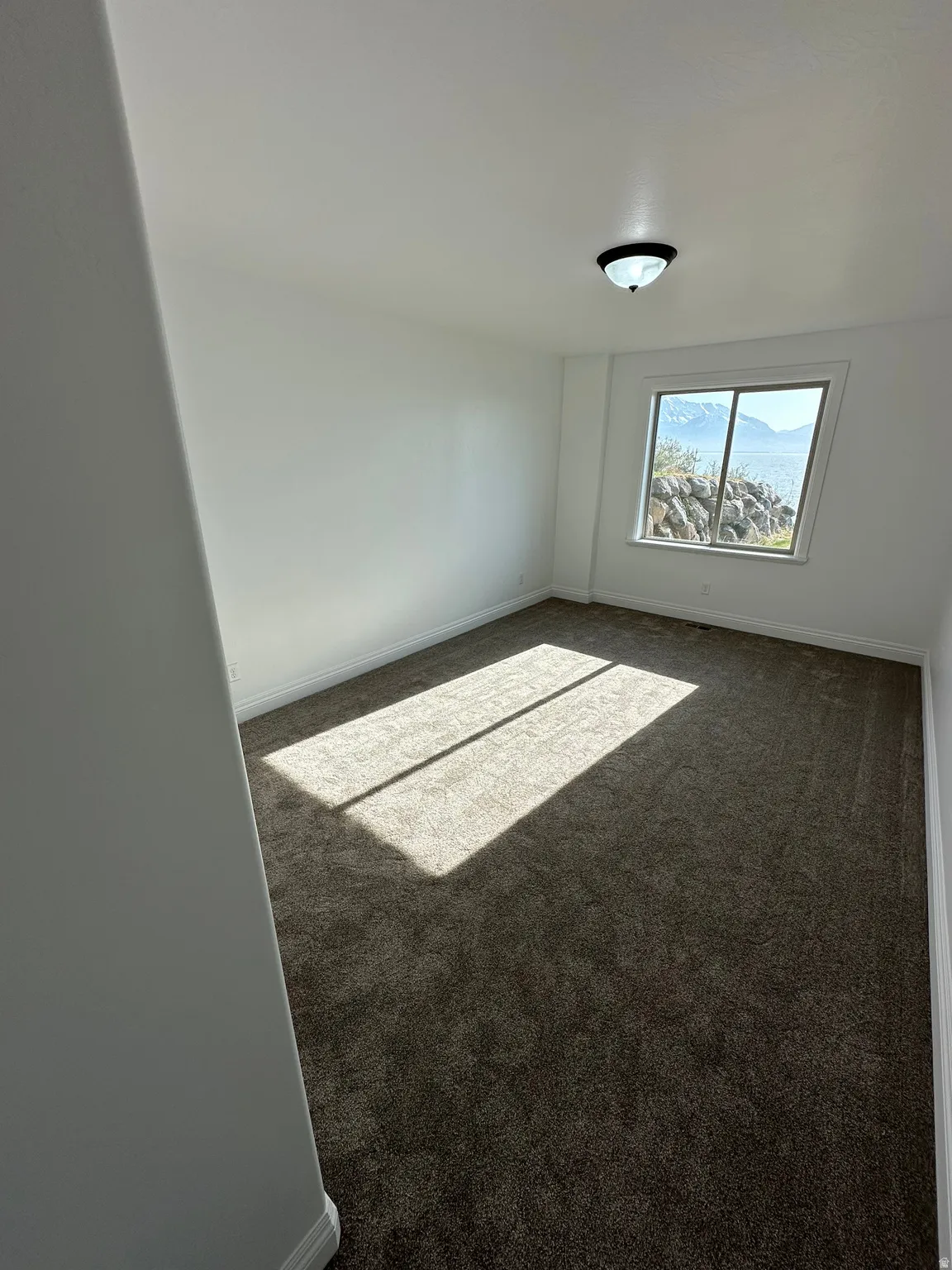 Spare room with baseboards and dark carpet