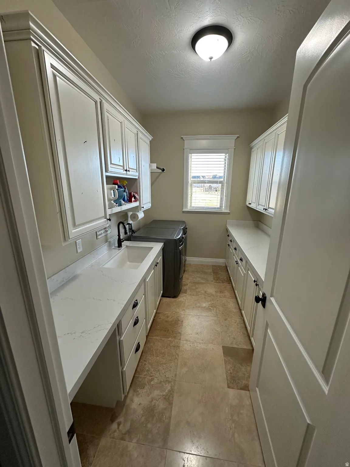 Laundry area with separate washer and dryer, cabinet space, and a textured ceiling