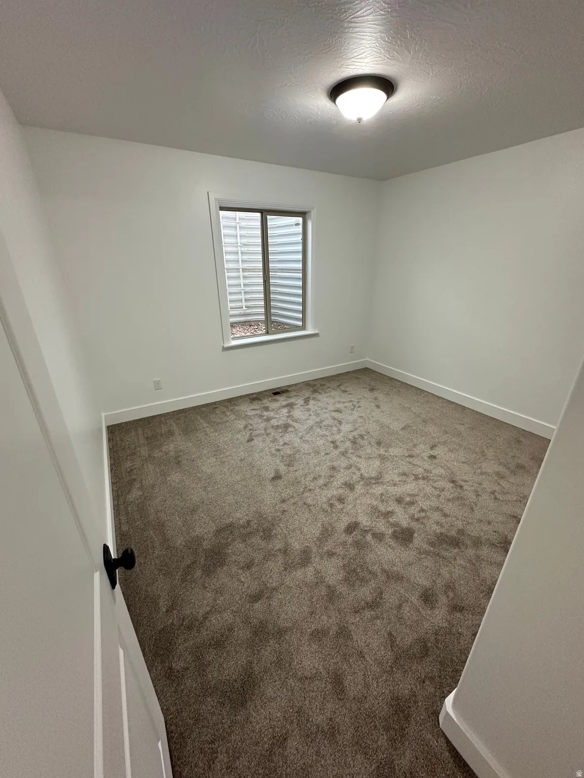 Spare room featuring a textured ceiling and dark carpet