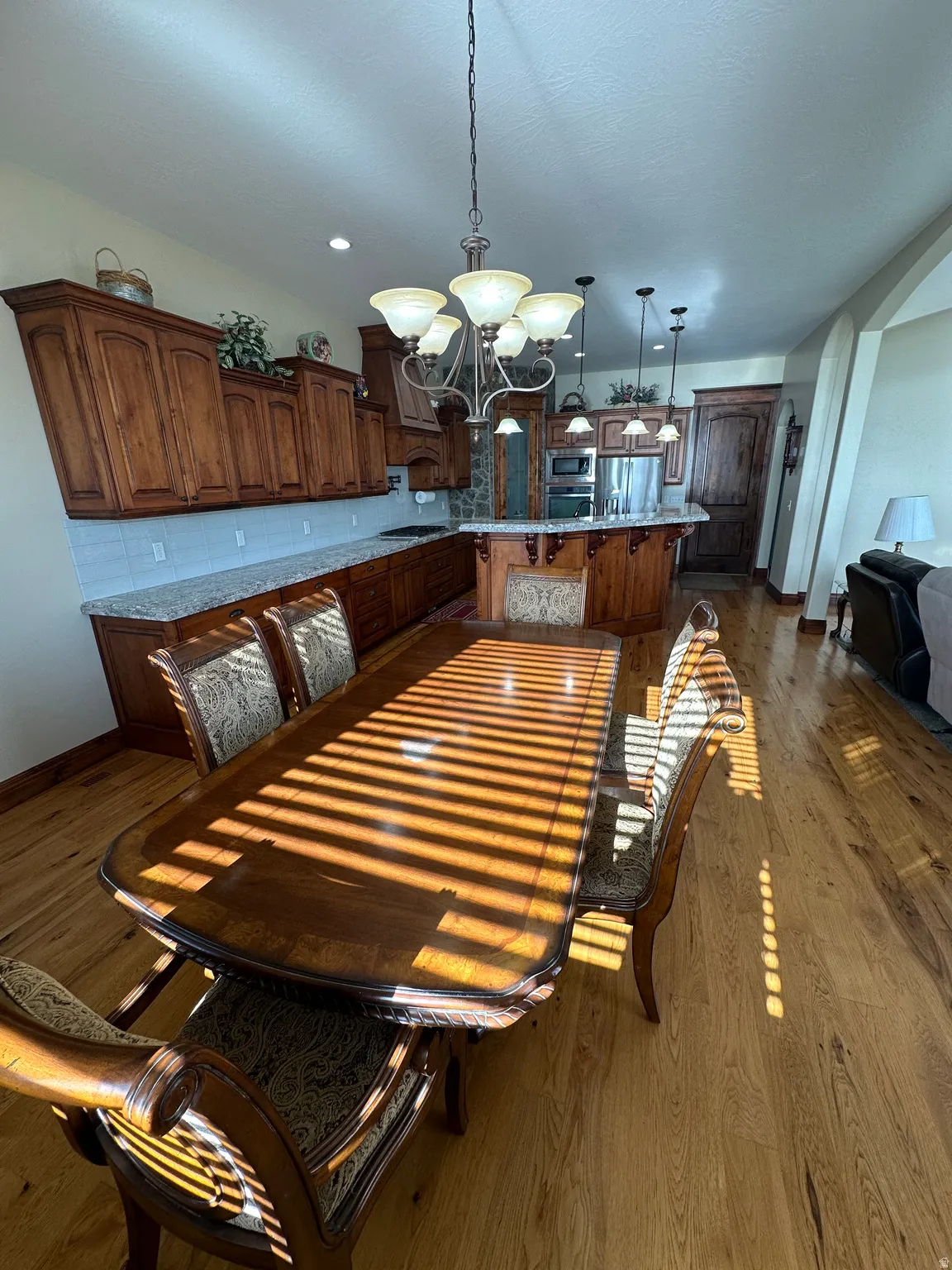 Dining room featuring dark wood-style flooring, a chandelier, and arched walkways