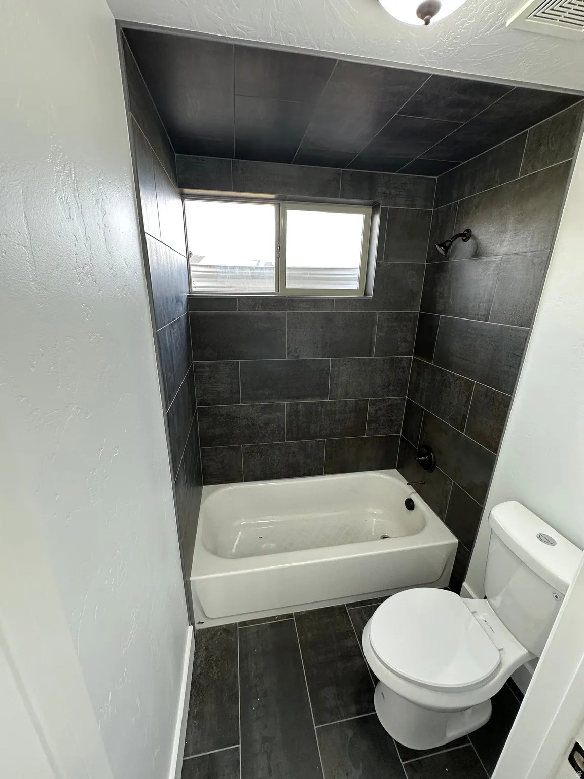 Full bathroom with shower / bath combination and dark tile patterned flooring