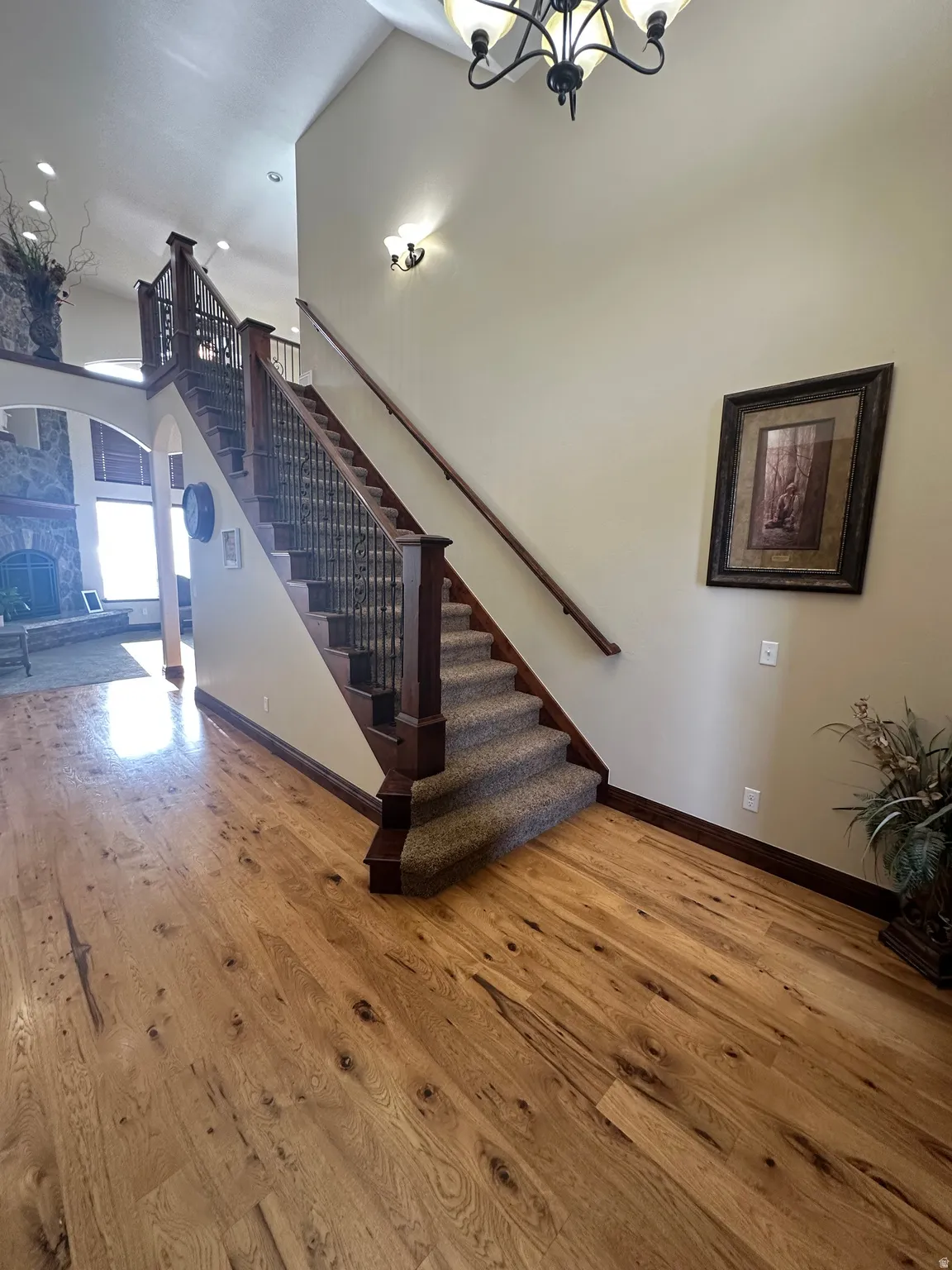 Stairway with hardwood / wood-style floors, arched walkways, a high ceiling, and hanging lights
