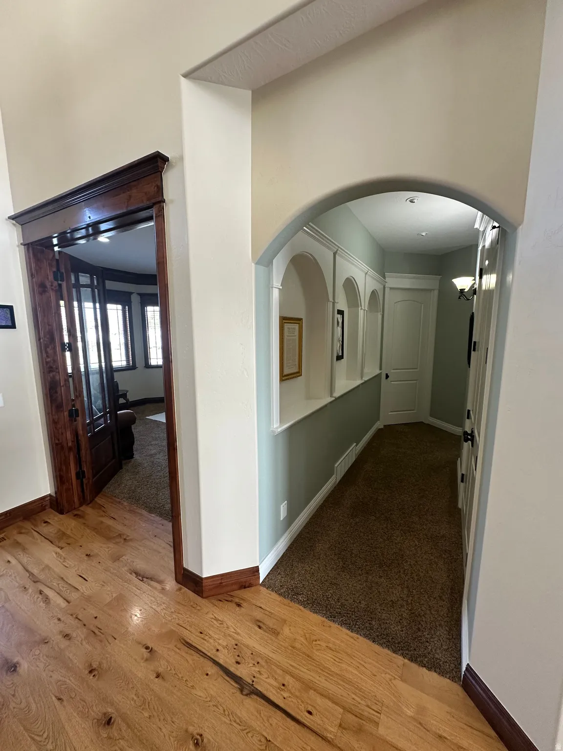 Corridor featuring arched walkways, dark wood finished floors, and dark colored carpet