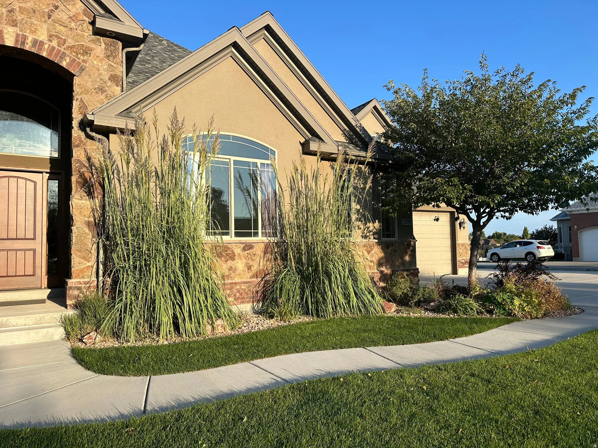 View of front of house featuring stone siding, a front lawn, stucco siding, and an attached garage
