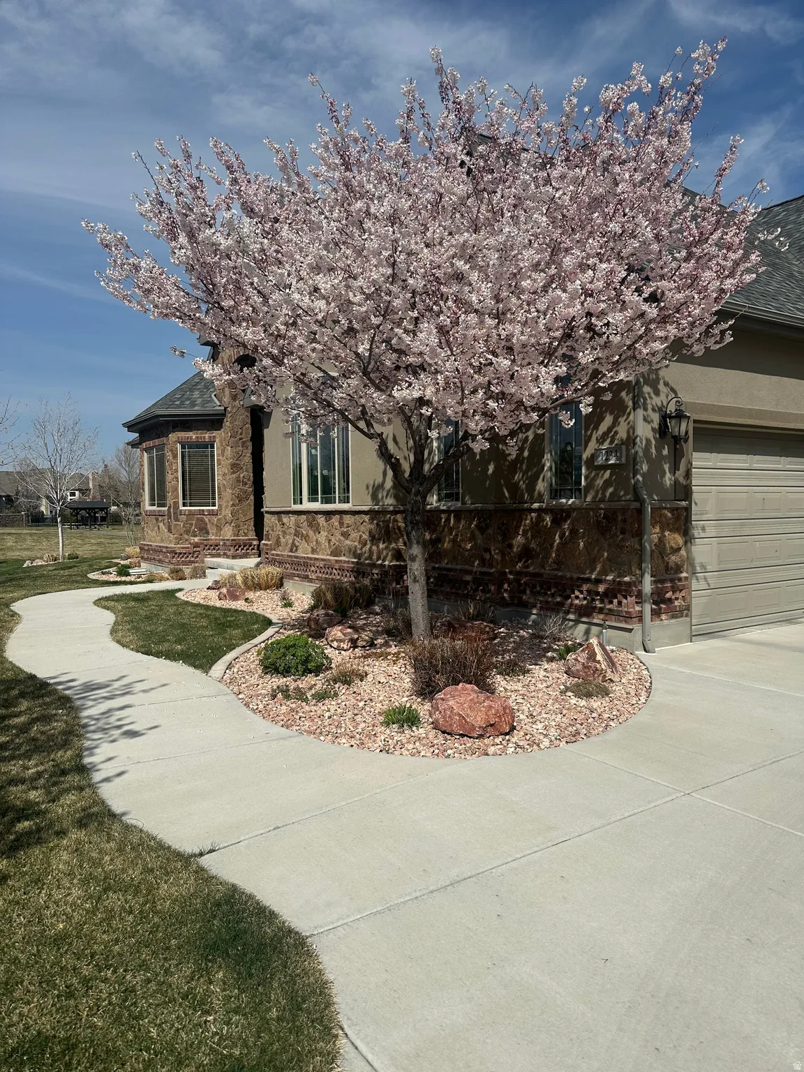 View of front of home featuring stucco siding, stone siding, an attached garage, driveway, and a shingled roof