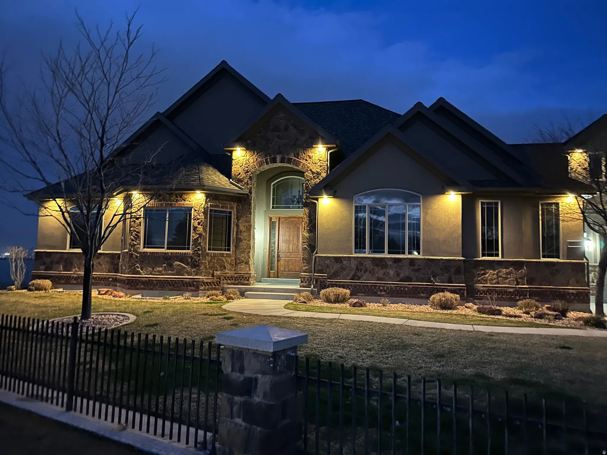 View of front of home featuring stone siding, a fenced front yard, and stucco siding