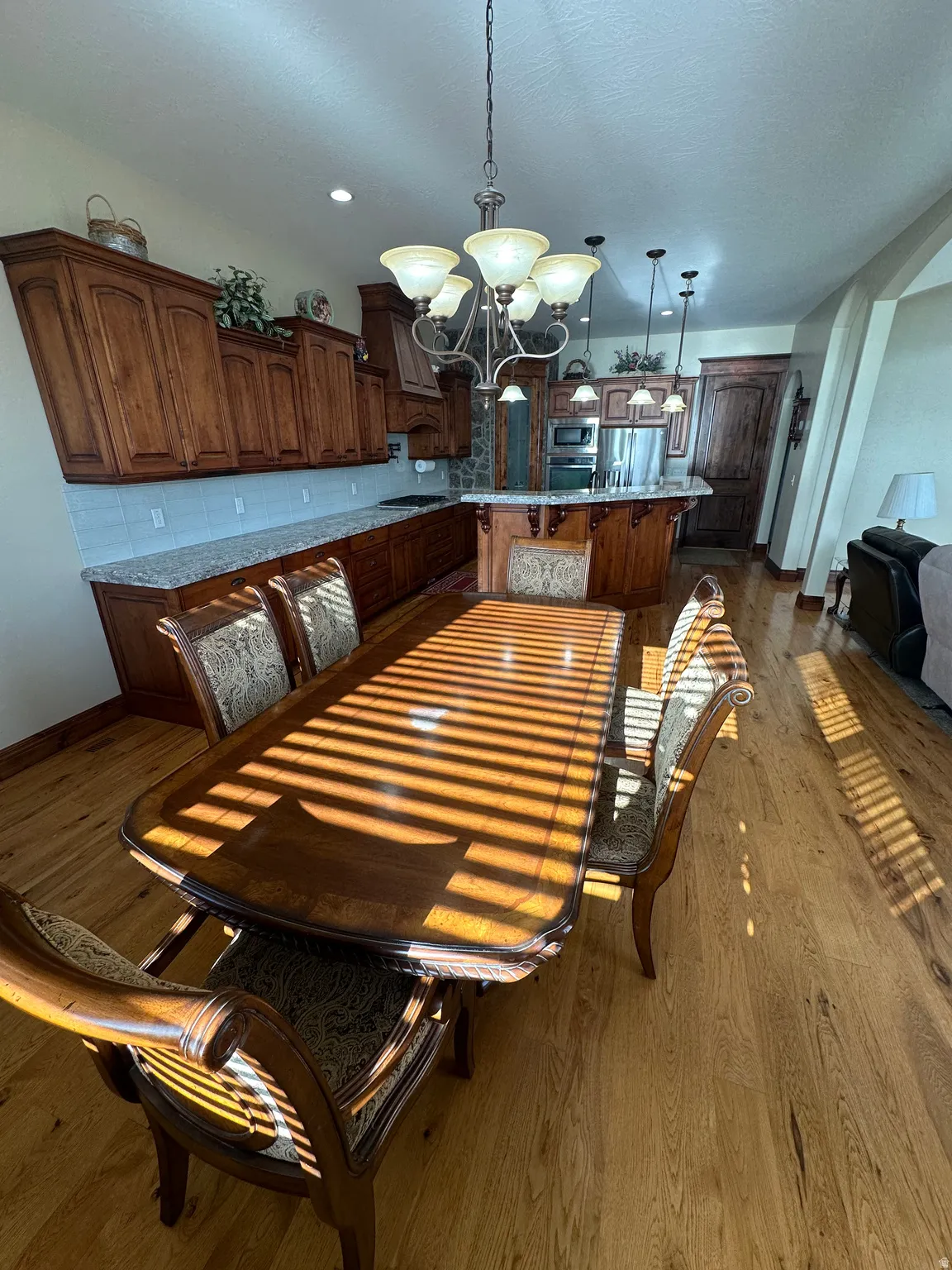 Dining area featuring dark wood-style flooring, suspended lighting, and arched walkways