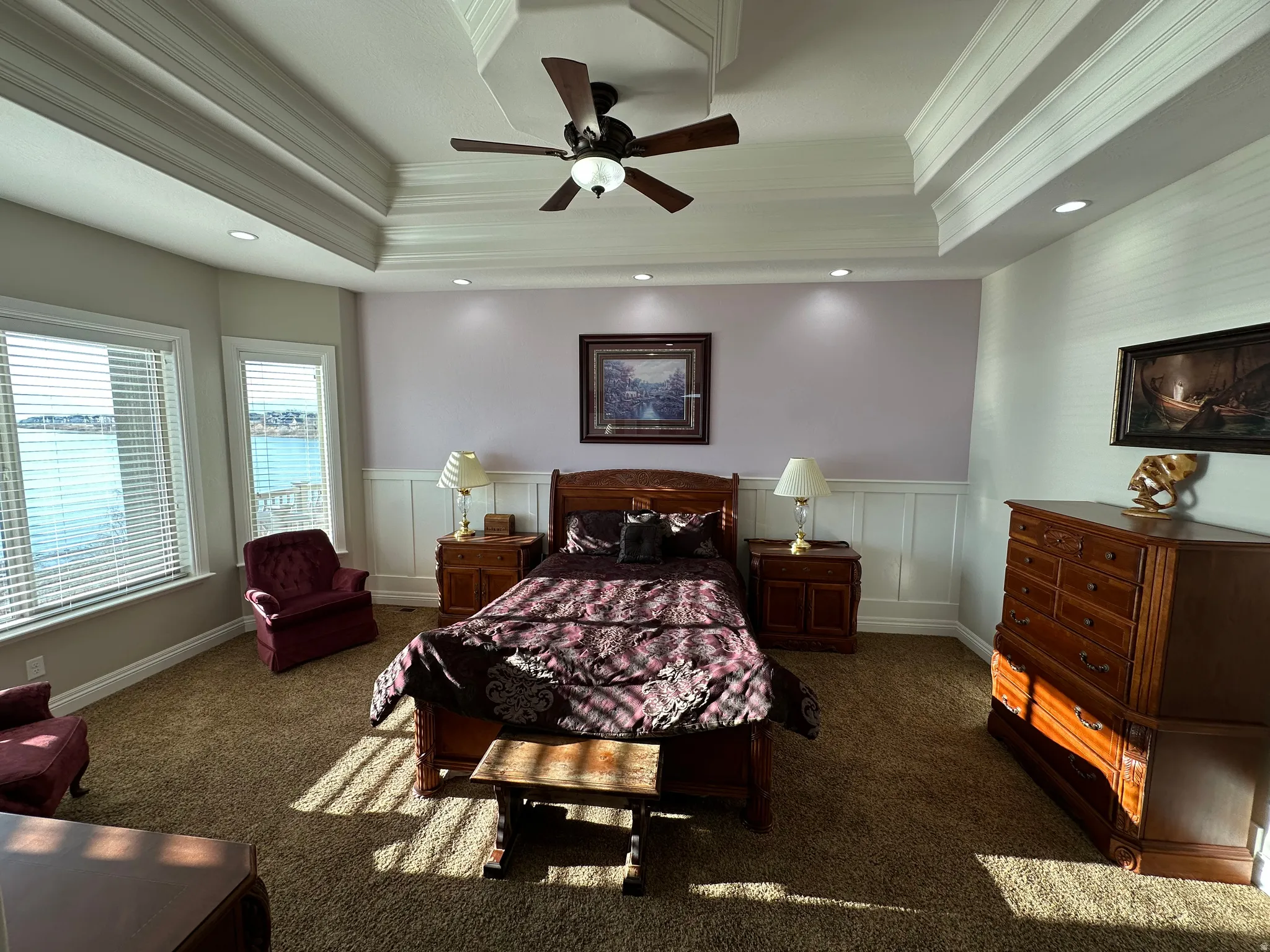Bedroom with a decorative wall, a wainscoted wall, ceiling fan, ornamental molding, and dark colored carpet