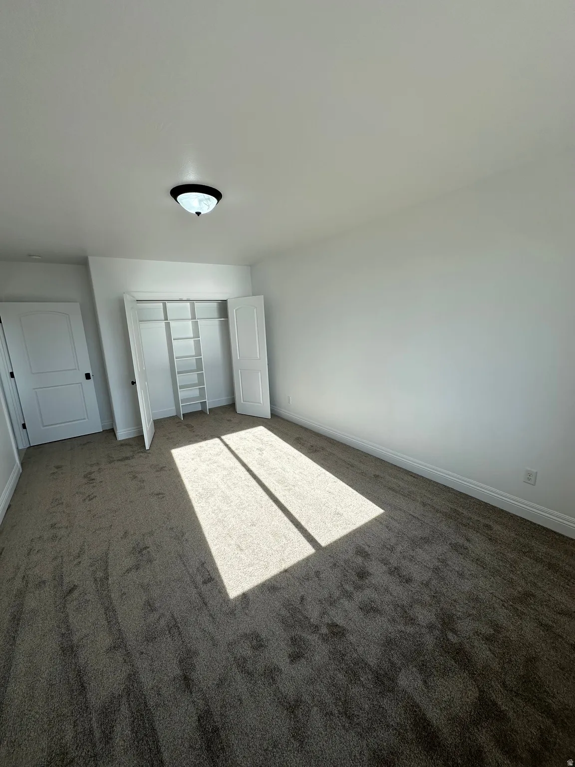 Unfurnished bedroom with dark colored carpet and a closet