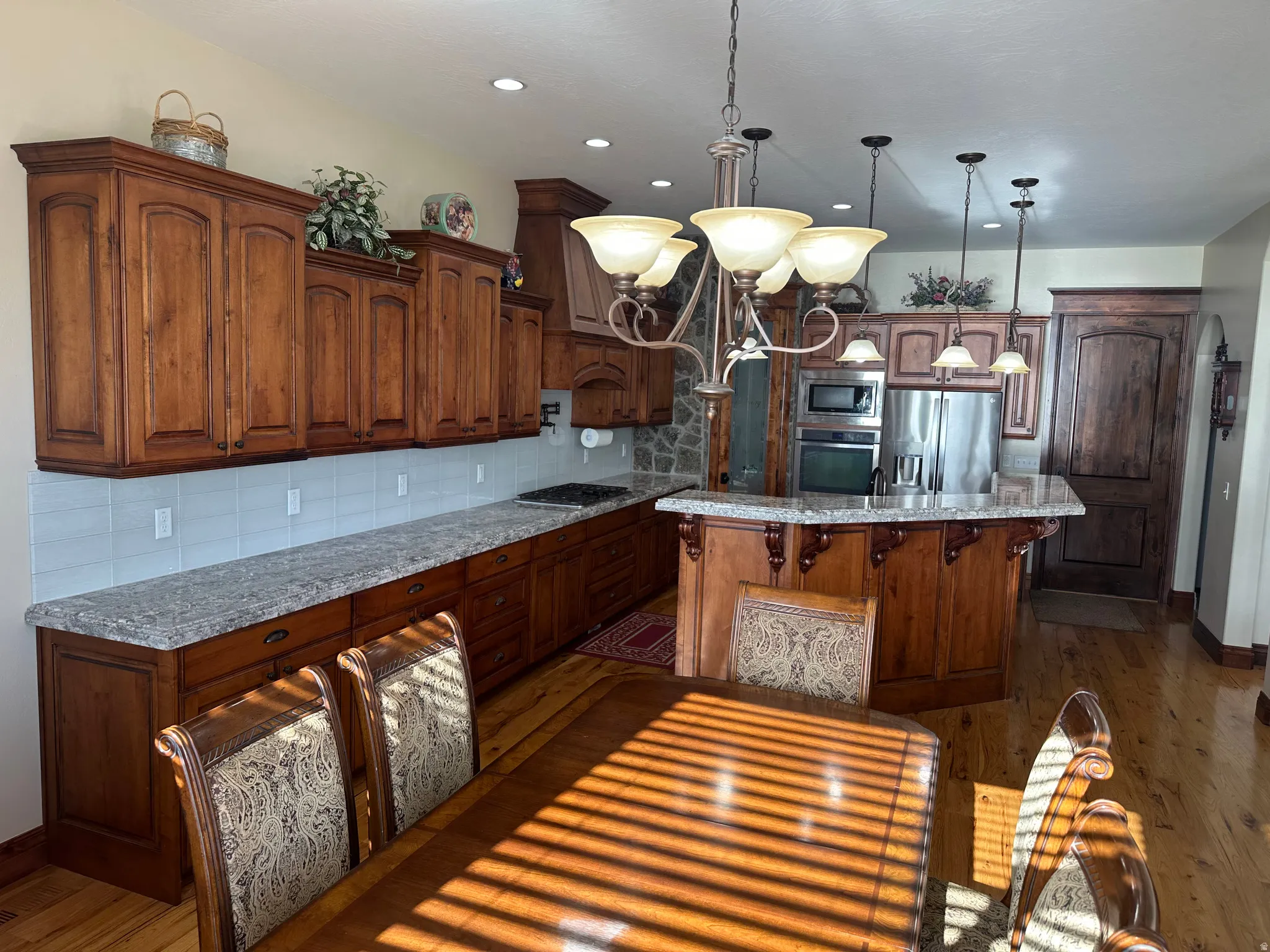 Kitchen featuring backsplash, dark wood finished floors, light stone countertops, a kitchen bar, and a kitchen island