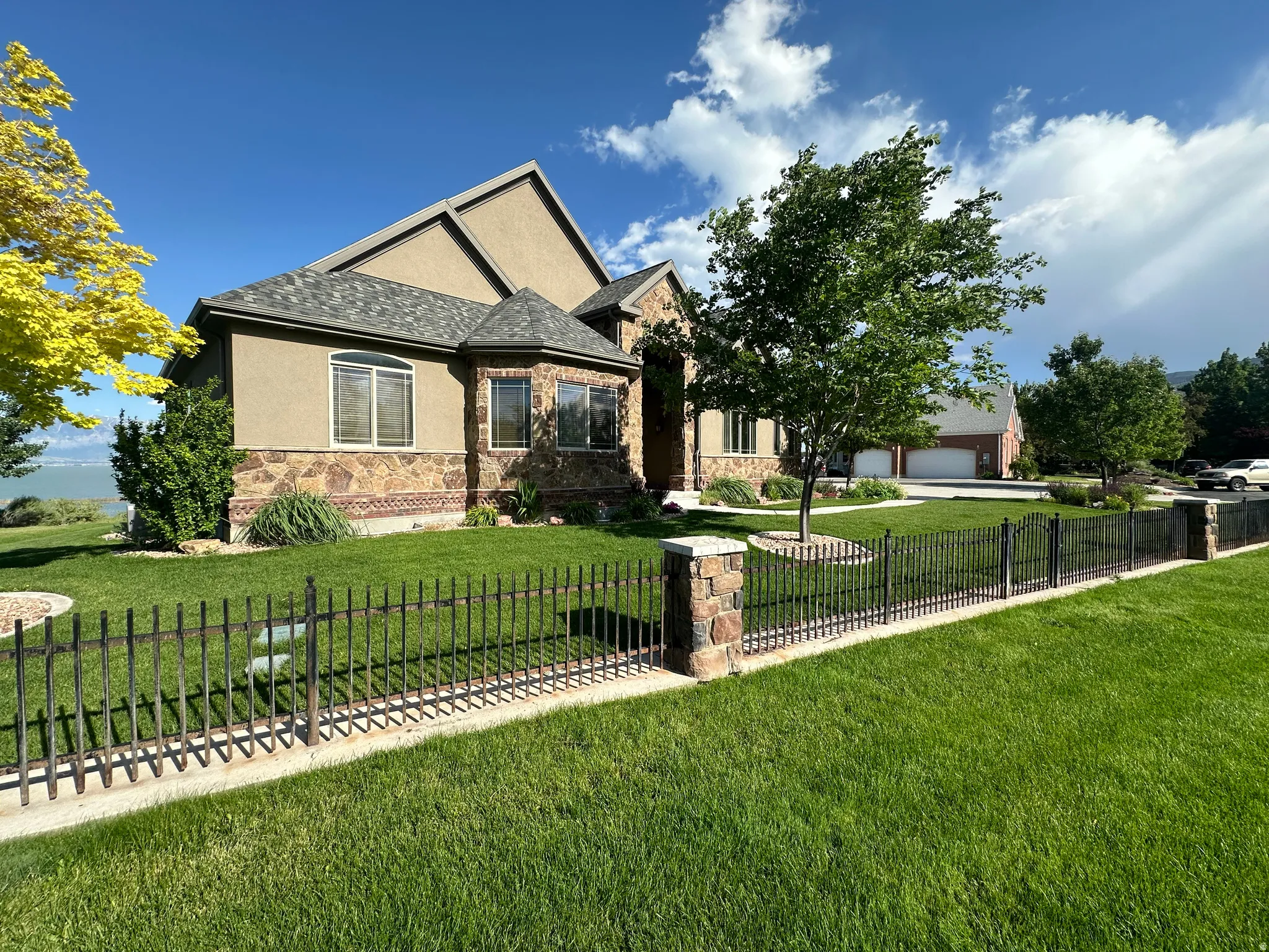 View of front of home with stucco siding, stone siding, a fenced front yard, and a garage