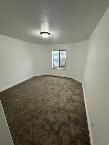 Empty room with dark carpet and a textured ceiling