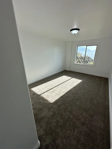 Spare room with baseboards and dark carpet