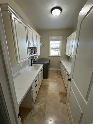 Laundry area with separate washer and dryer, cabinet space, and a textured ceiling