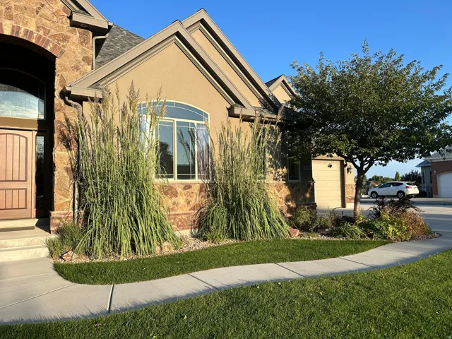 View of front of house featuring stone siding, a front lawn, stucco siding, and an attached garage