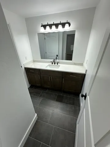 Bathroom featuring vanity, dark tile patterned flooring, and a textured wall