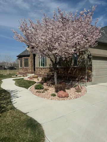 View of front of home featuring stucco siding, stone siding, an attached garage, driveway, and a shingled roof