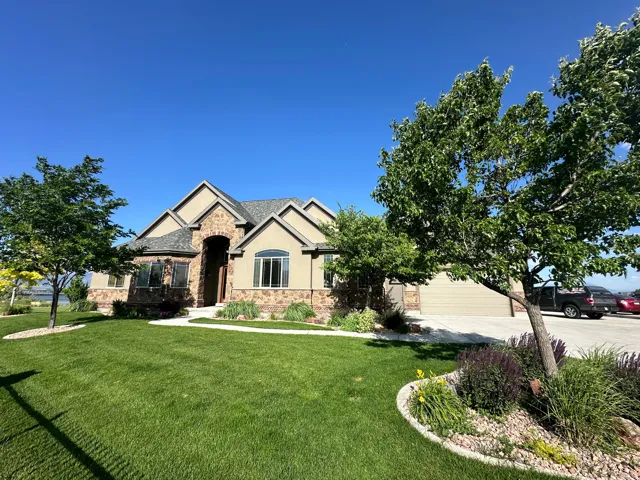 View of front facade featuring stone siding, concrete driveway, a front yard, stucco siding, and a garage