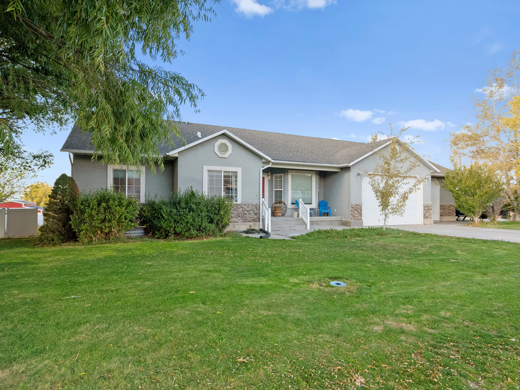 Ranch-style house with a front yard, a garage, stucco siding, and roof with shingles