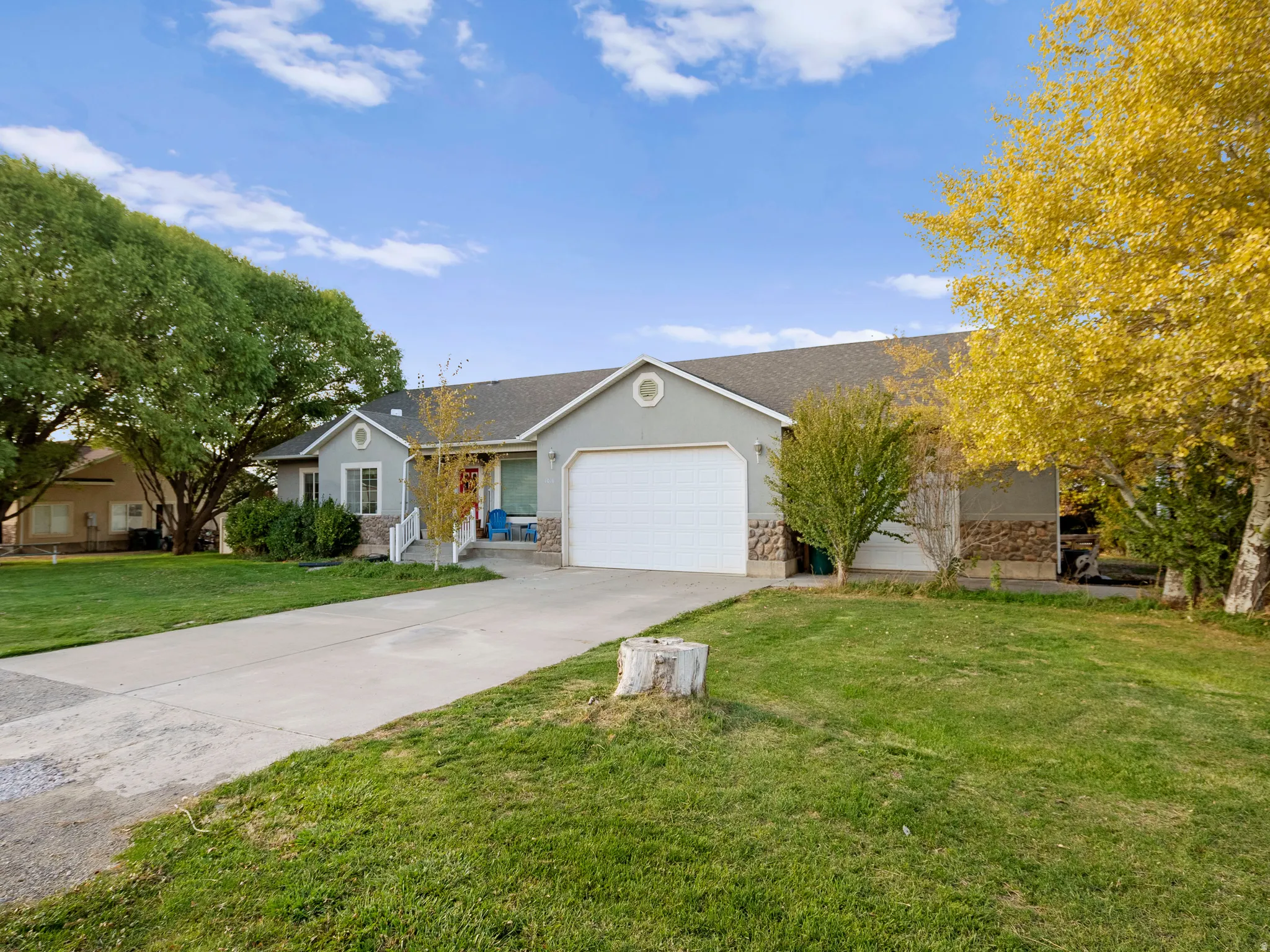 Ranch-style home with driveway, stucco siding, a front lawn, a garage, and roof with shingles