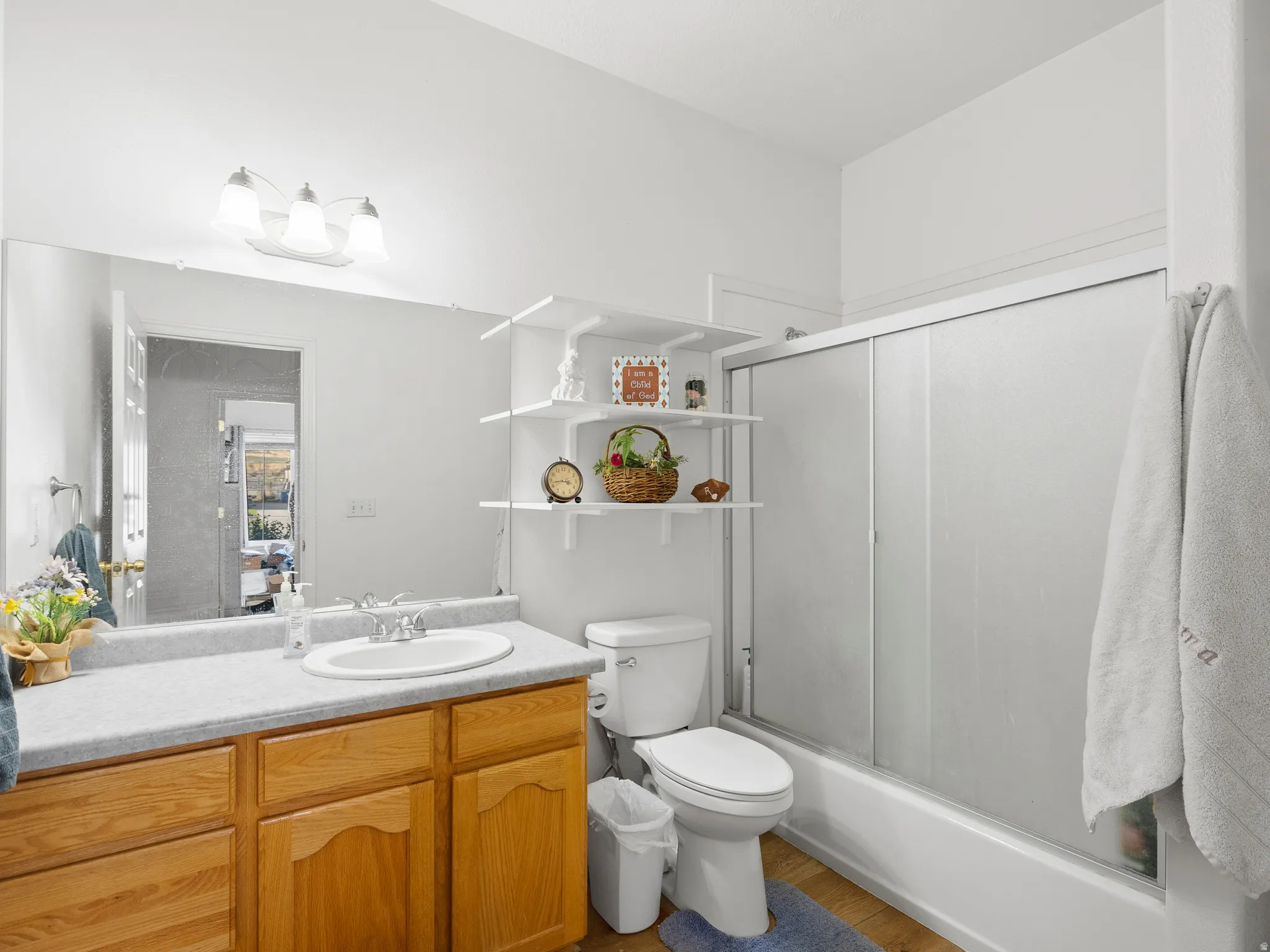 Full bathroom featuring vanity, combined bath / shower with glass door, and dark wood-style floors