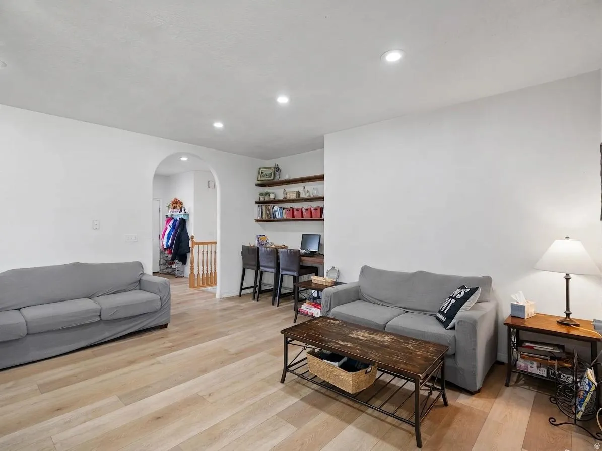 Living room with light wood-type flooring, arched walkways, an office area, and recessed lighting