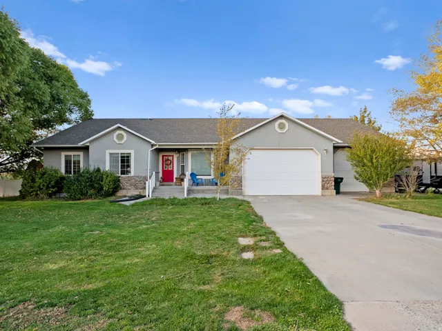 Ranch-style home featuring a garage, stucco siding, driveway, and a front lawn