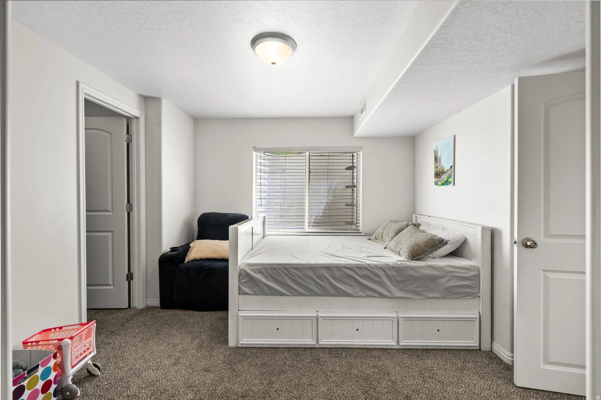 Bedroom with dark carpet and a textured ceiling