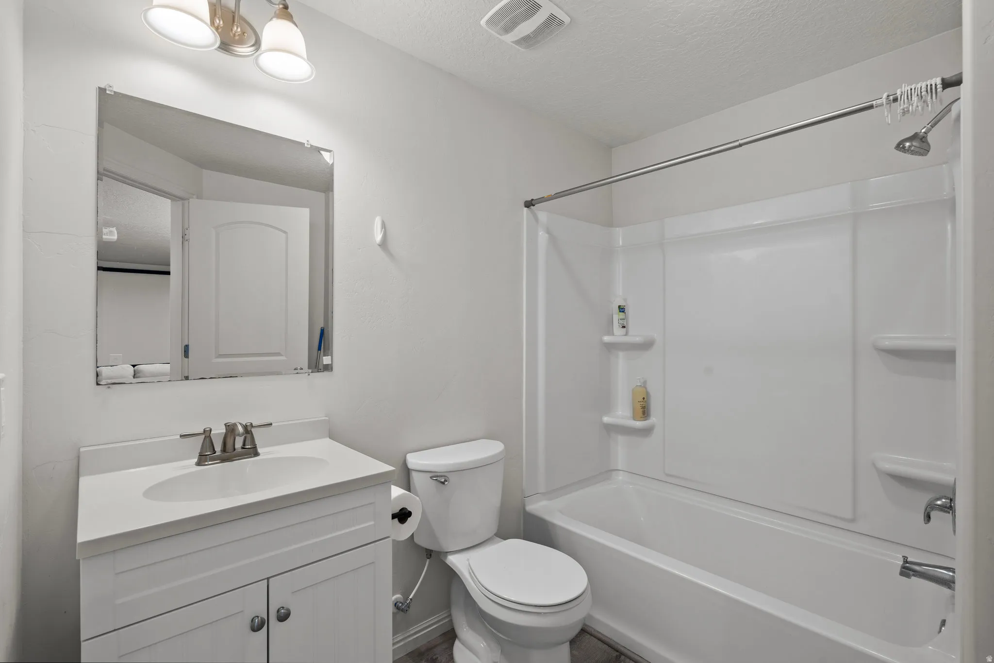 Bathroom with vanity, washtub / shower combination, and a textured ceiling