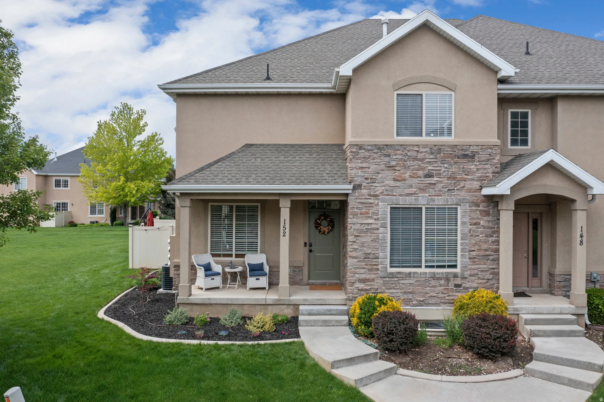 View of front of property featuring stucco siding, a front lawn, stone siding, and roof with shingles