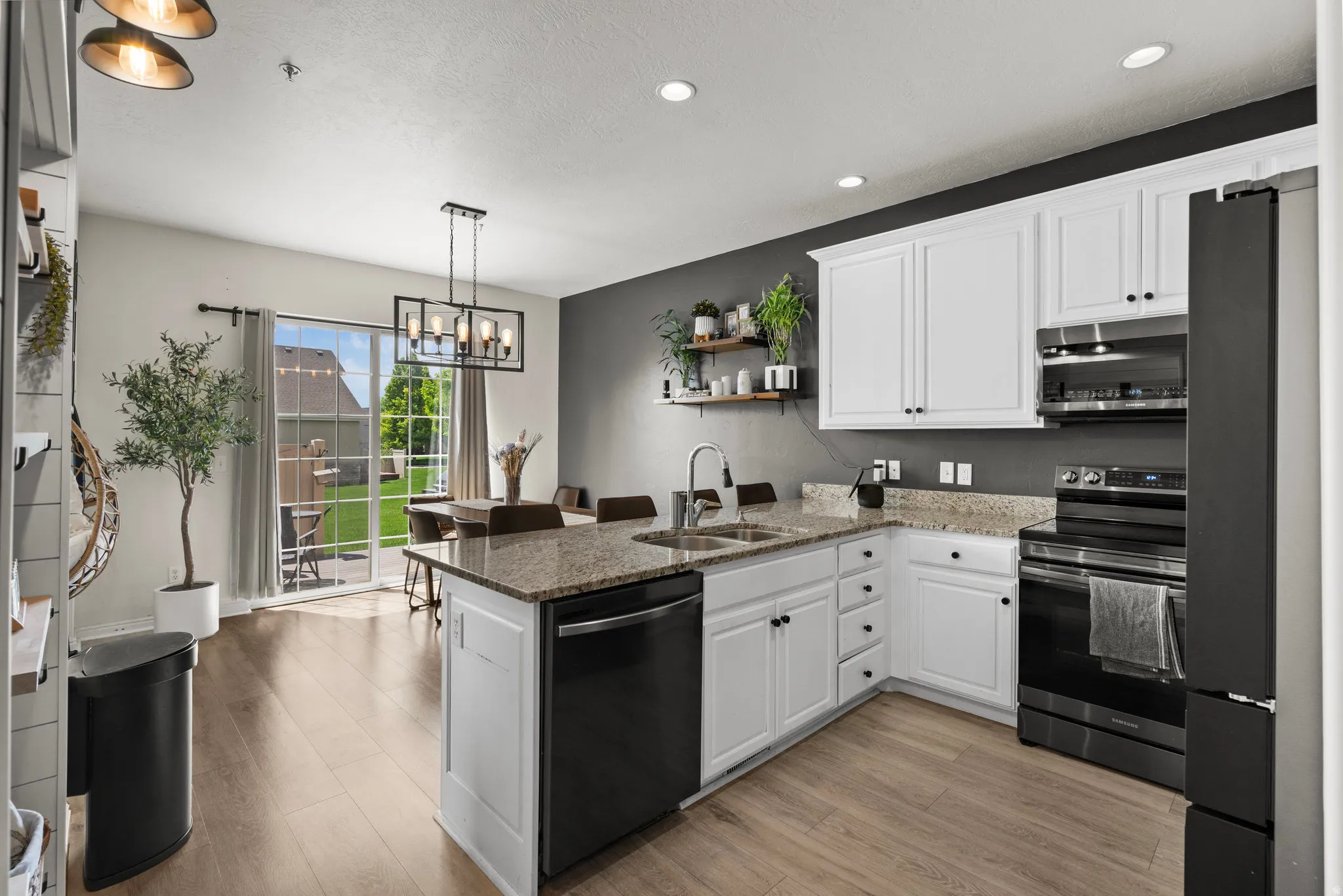 Kitchen featuring dark stone countertops, stainless steel appliances, white cabinets, a peninsula, and open shelves