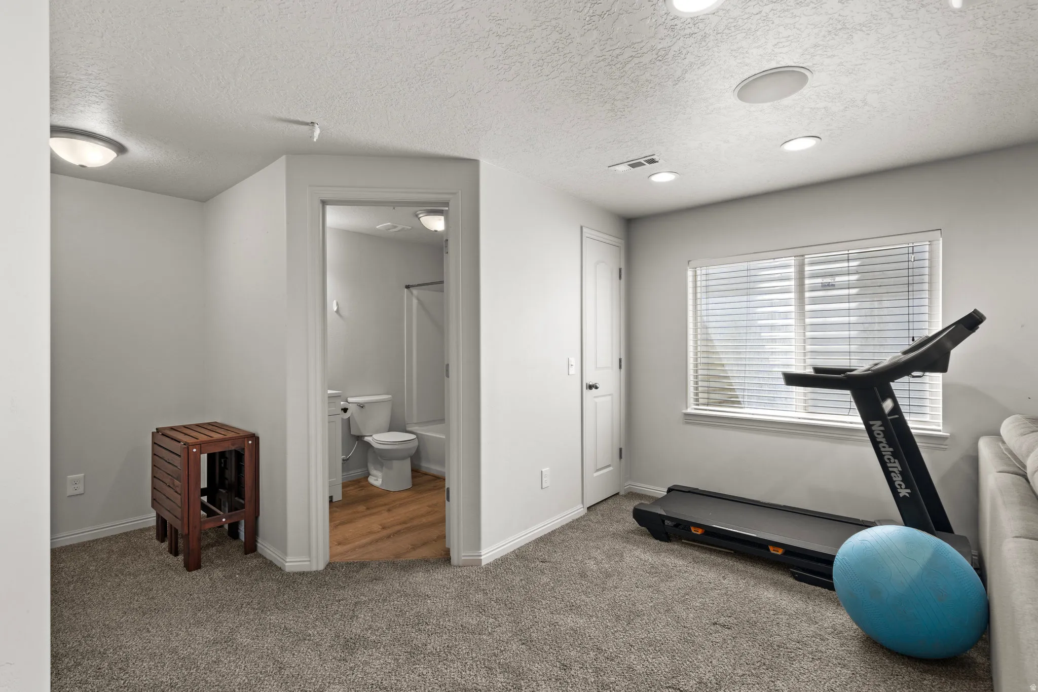 Workout room with a textured ceiling, carpet floors, and recessed lighting