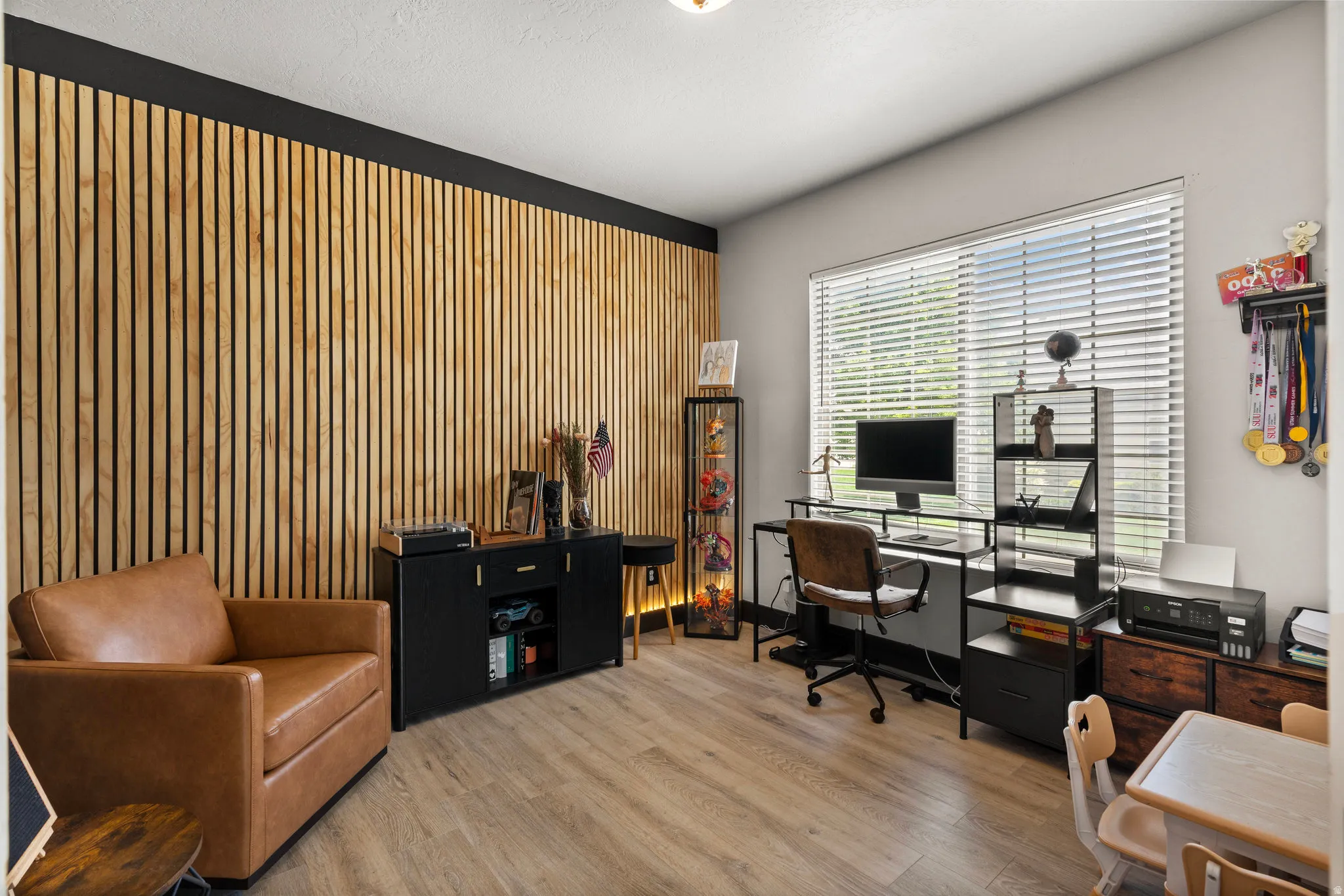 Office featuring light wood-type flooring, wooden walls, and an accent wall