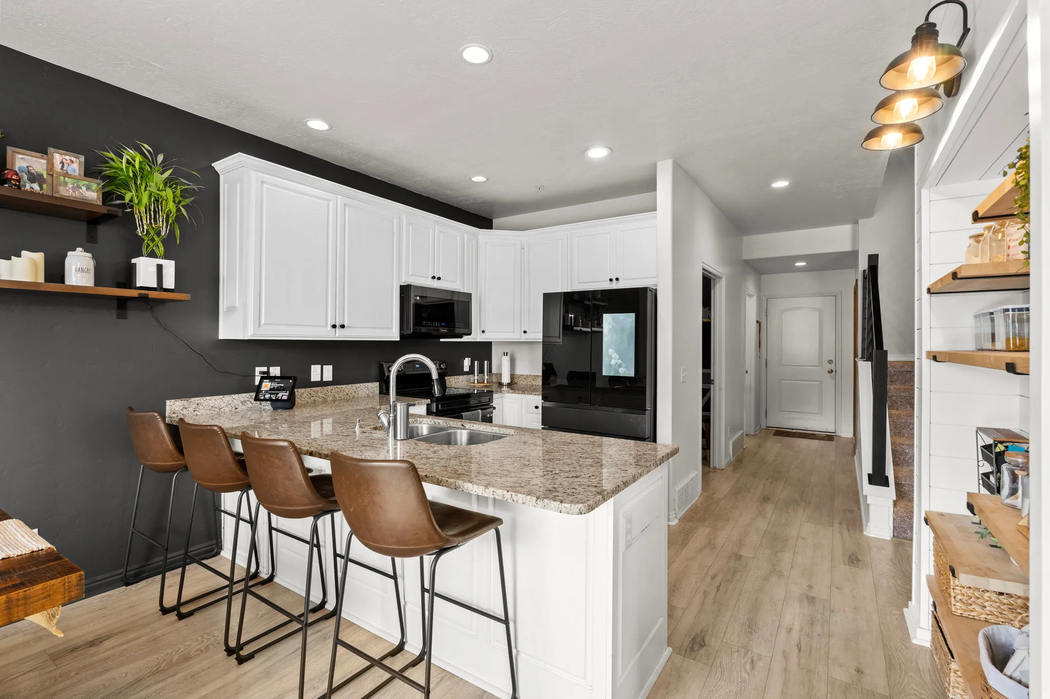 Kitchen featuring open shelves, white cabinets, freestanding refrigerator, light stone countertops, and light wood-style flooring