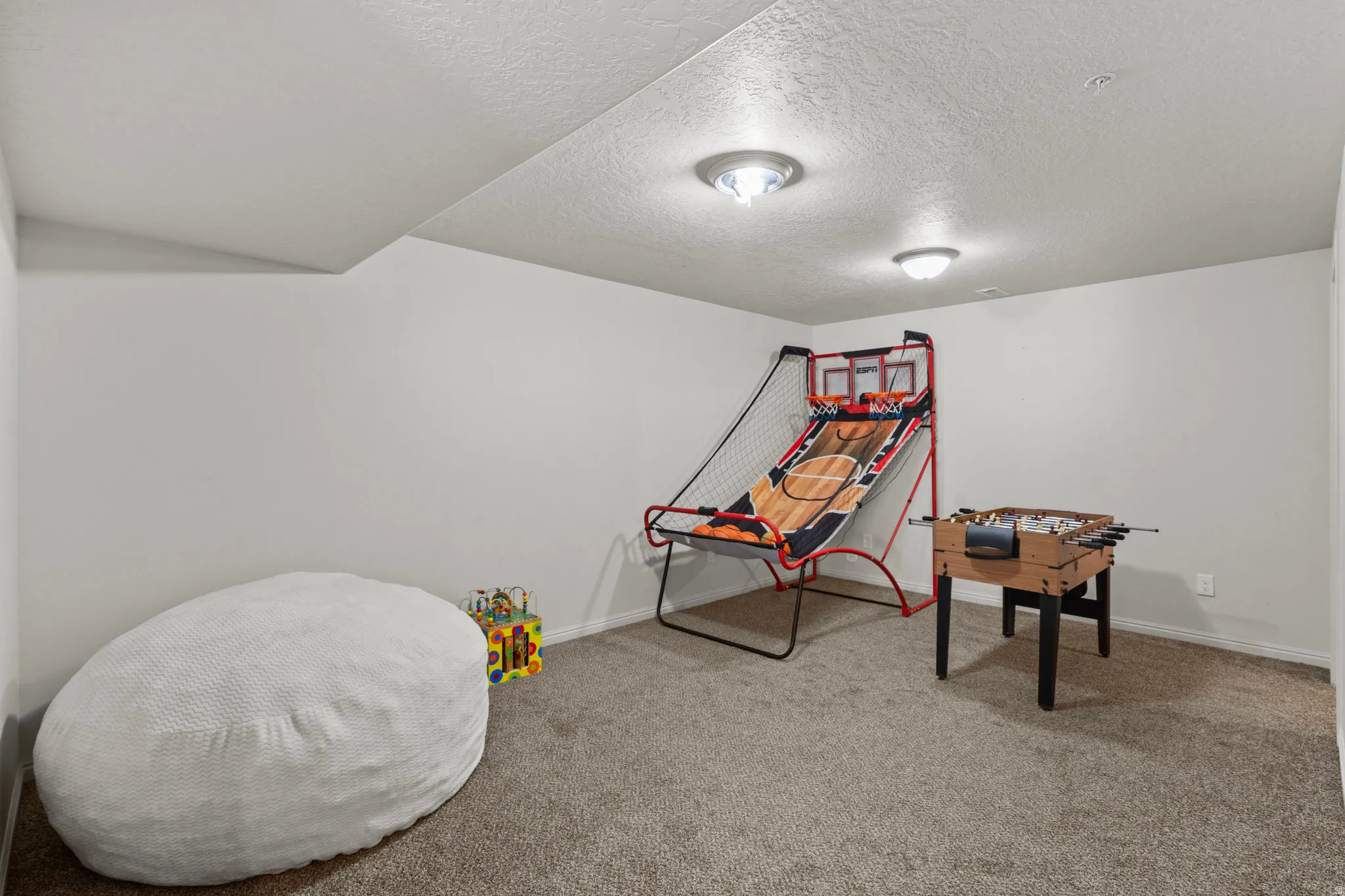 Playroom with a textured ceiling and light carpet