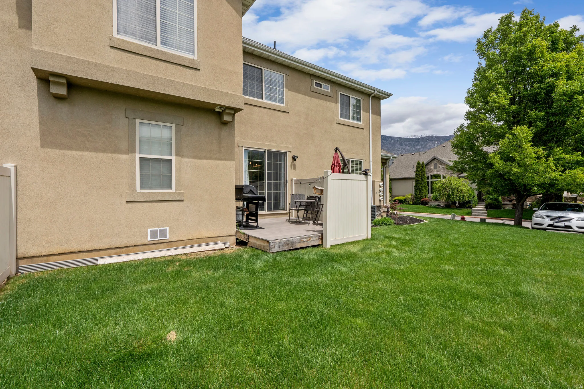 Back of house with a wooden deck, stucco siding, and a lawn