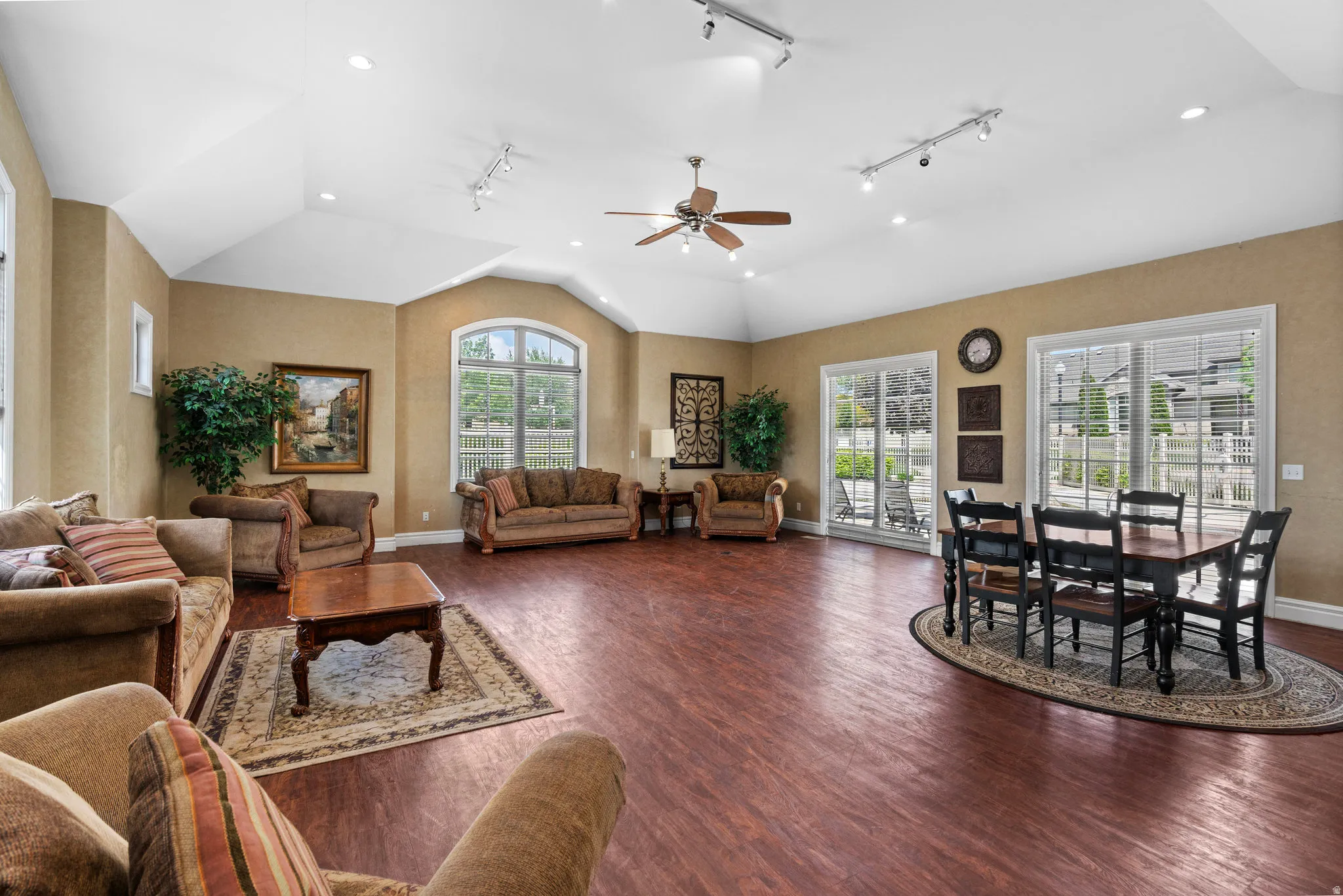 Living area with vaulted ceiling, rail lighting, a ceiling fan, and dark wood finished floors
