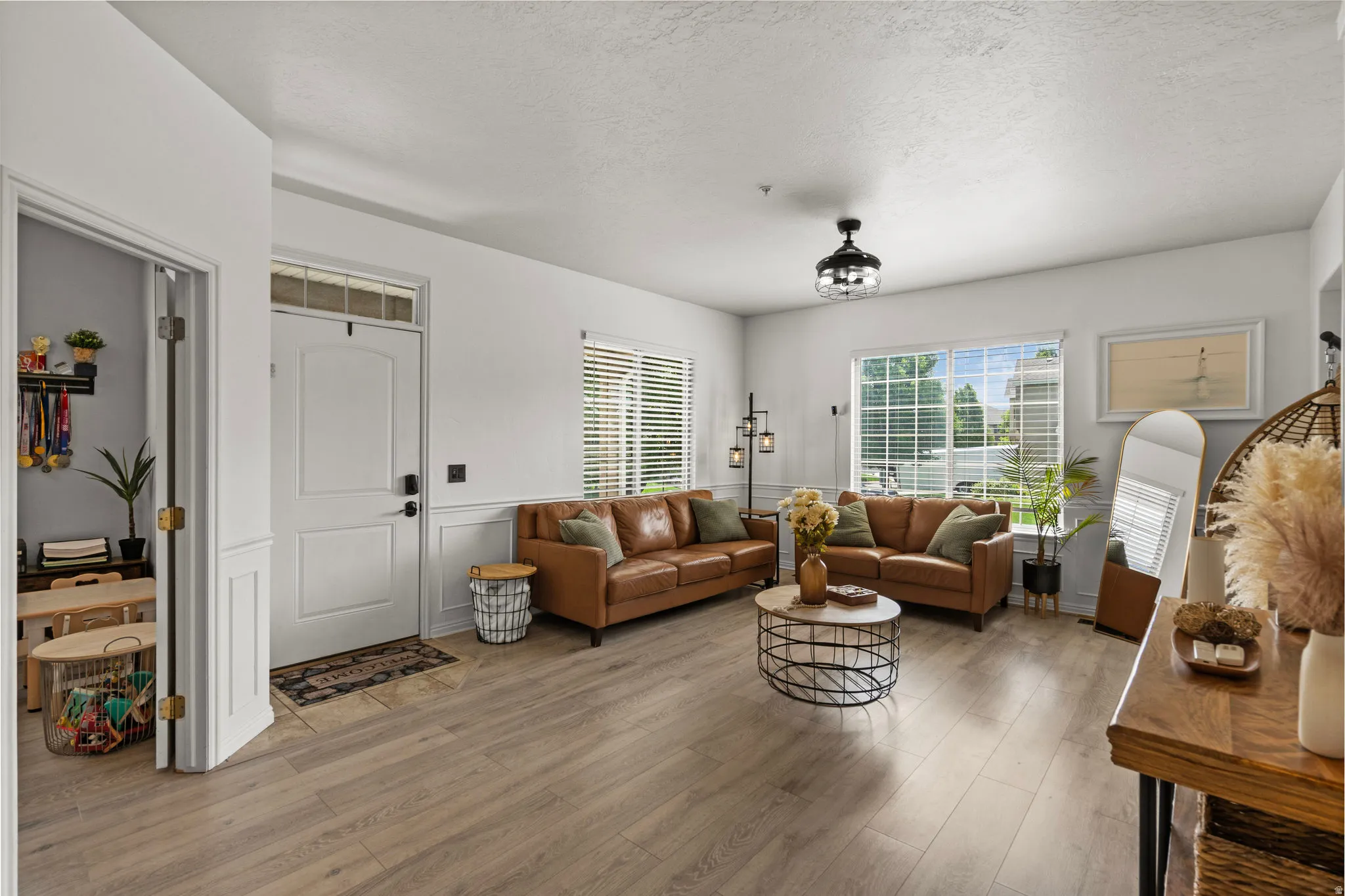 Living room featuring wood finished floors, a textured ceiling, and a wainscoted wall