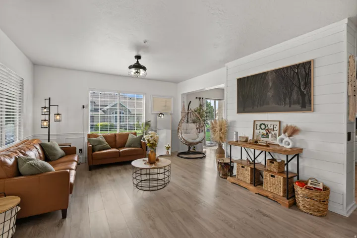 Living area featuring light wood-type flooring, a textured ceiling, and wood walls
