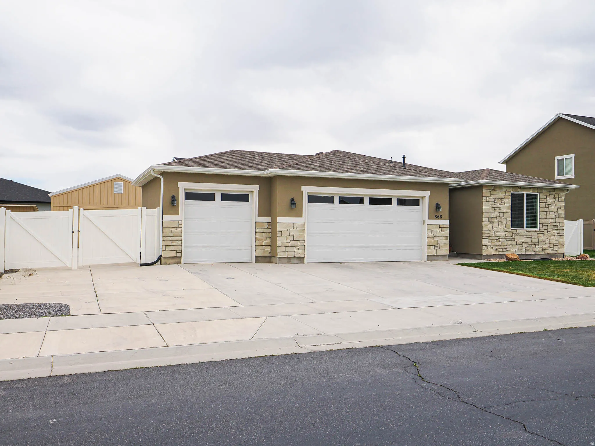 View of front of property with a gate, stone siding, an attached garage, and concrete driveway
