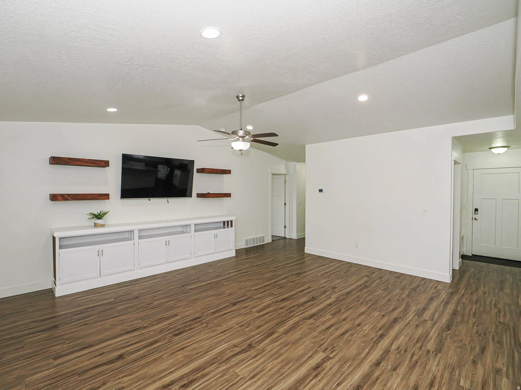 Unfurnished living room featuring ceiling fan, dark wood finished floors, and recessed lighting