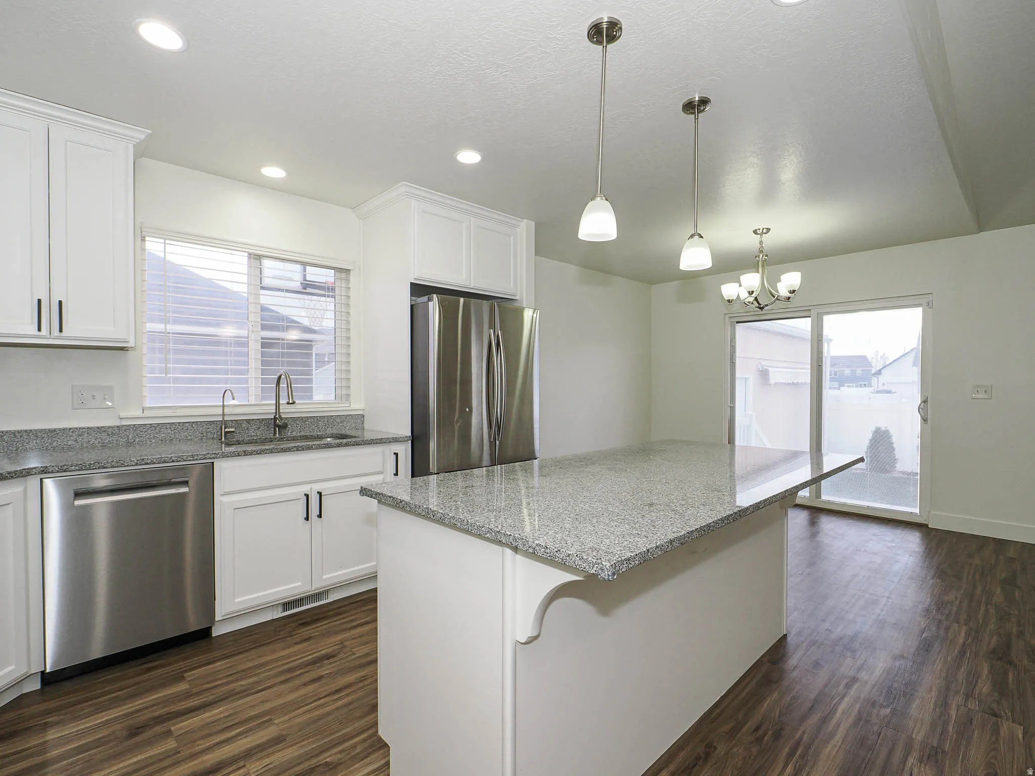 Kitchen featuring light stone countertops, white cabinetry, stainless steel appliances, dark wood-style flooring, and a textured ceiling