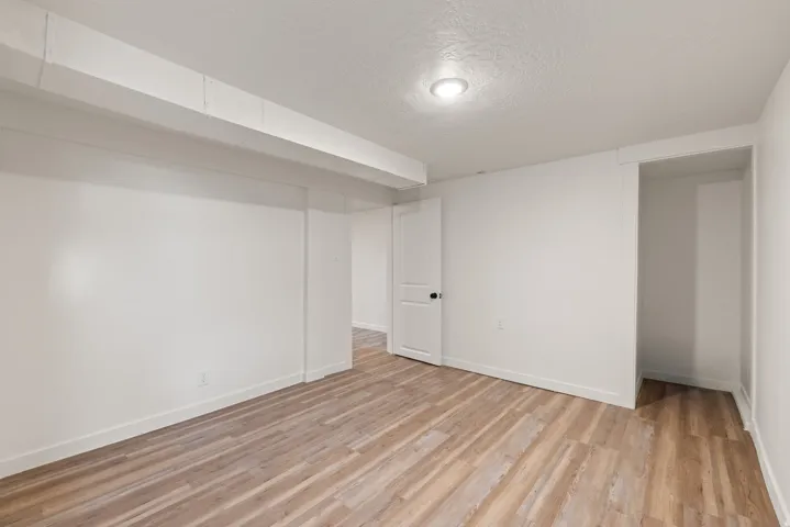 Finished below grade area with a textured ceiling and light wood-style flooring
