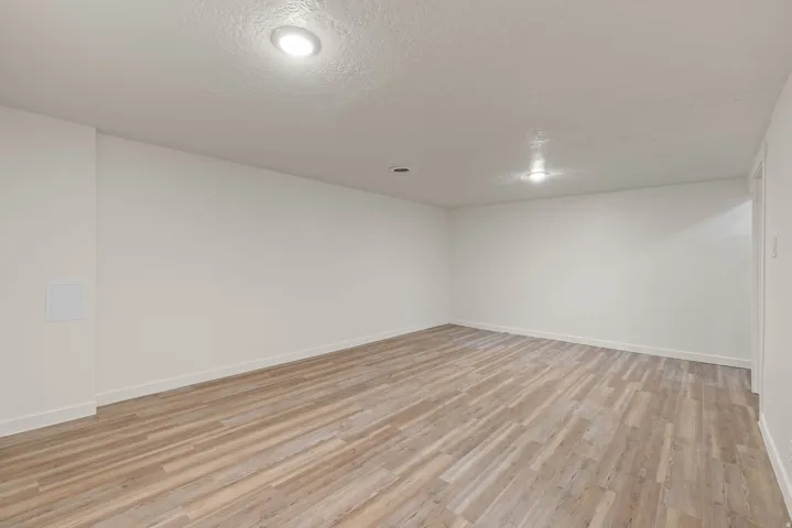 Empty room featuring light wood finished floors and a textured ceiling