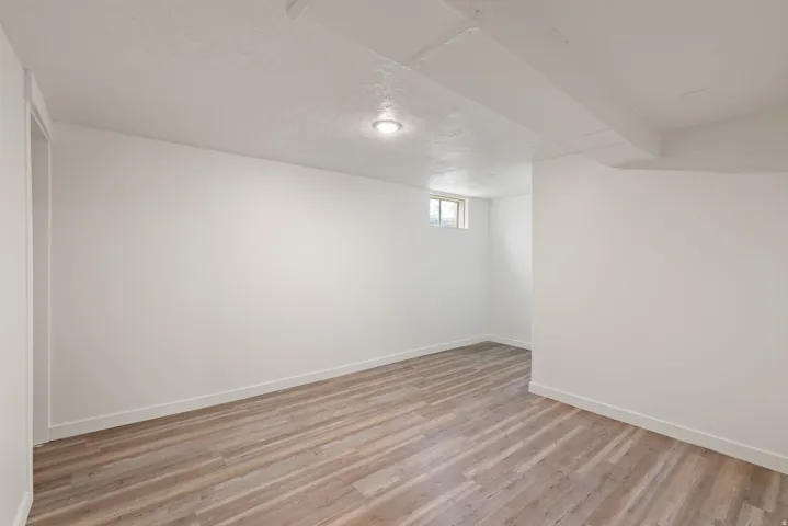 Below grade area with light wood-style floors and a textured ceiling